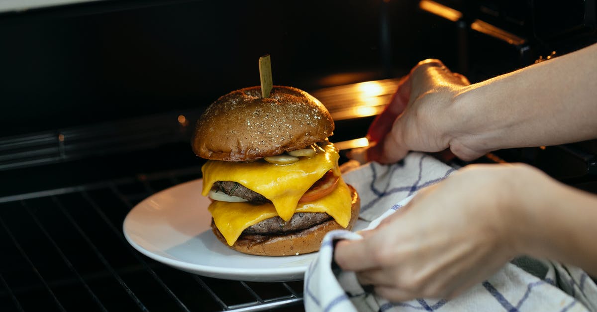 Toasting bagel in my oven - From above of unrecognizable person using towel to place burger served on plate in hot oven on rack while cooking Toasting bagel in my oven - From above of unrecognizable person using towel to place burger served on plate in hot oven on rack while cooking