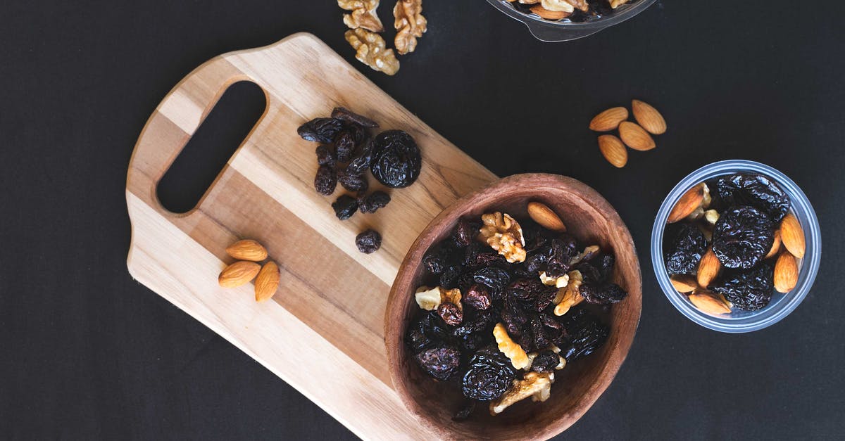 Toasting chopped almonds - Raisins and Nuts on Different Kinds of Bowl on the Black Surface Toasting chopped almonds - Raisins and Nuts on Different Kinds of Bowl on the Black Surface
