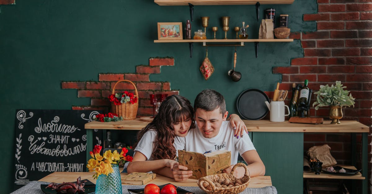 tortilla recipe with longest shelf life - Positive Asian couple embracing while reading recipe book together sitting at table in kitchen