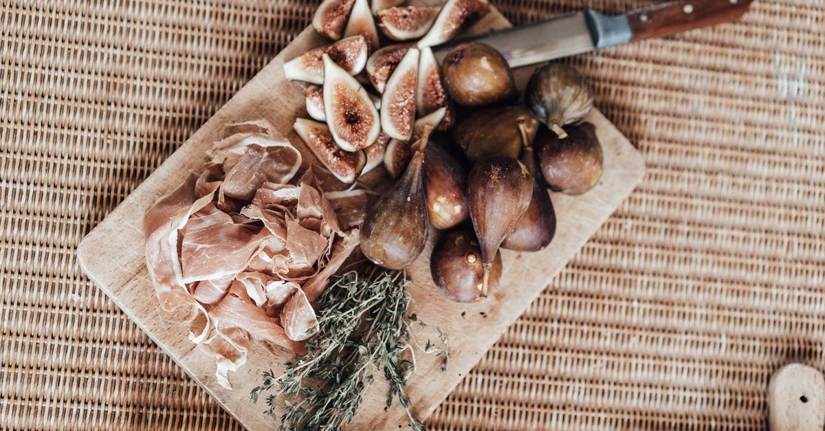 Traditionally, is prosciutto never to be cooked? - Cut figs on wooden board with ham Traditionally, is prosciutto never to be cooked? - Cut figs on wooden board with ham