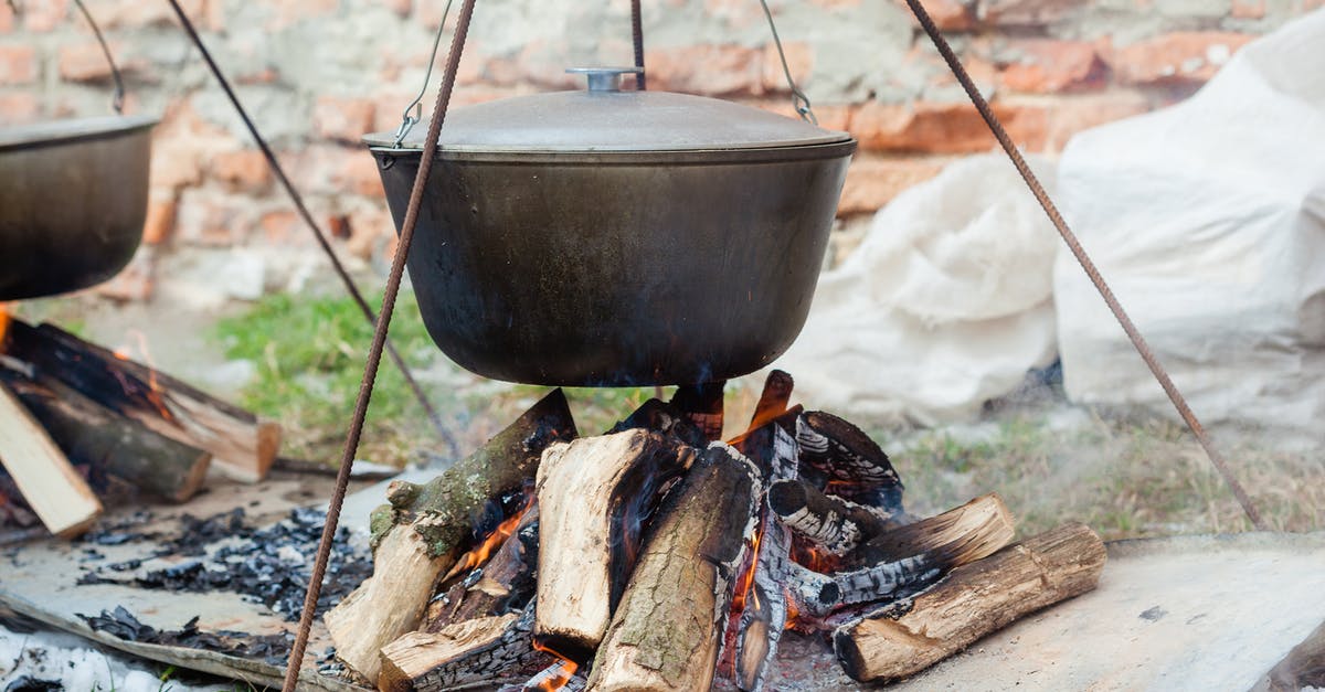 Tramontina lid stuck to pot - Metal pots hanging over burning cut tree trunks on metal sheet in daytime on blurred background Tramontina lid stuck to pot - Metal pots hanging over burning cut tree trunks on metal sheet in daytime on blurred background