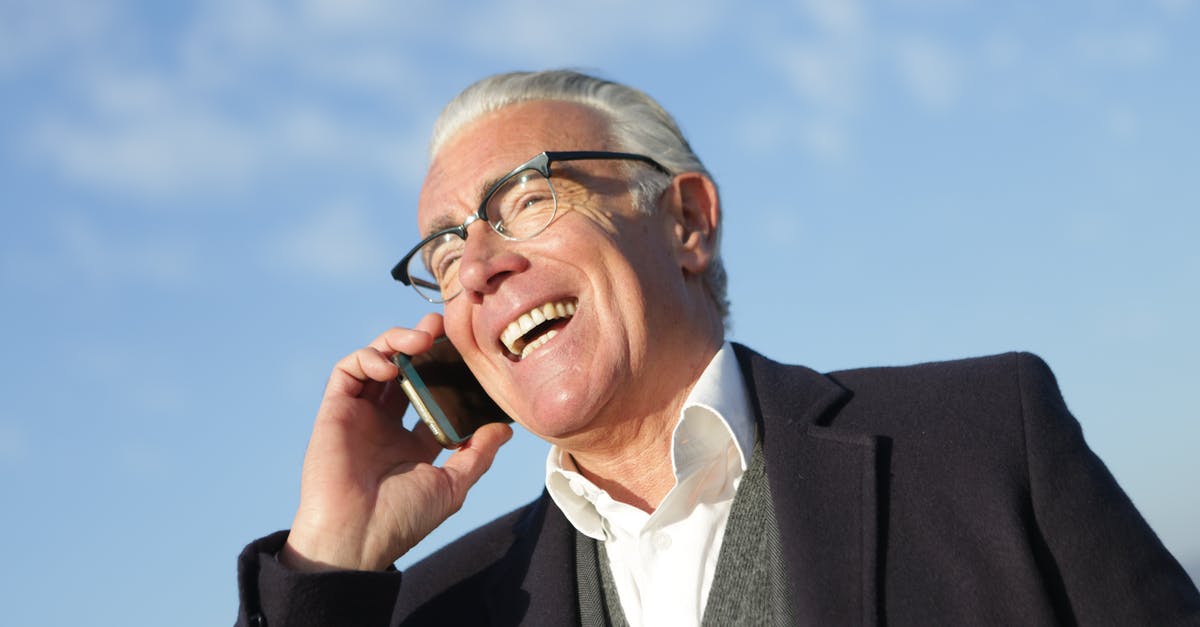turkish delight is "grainy" - From below of delighted aged male entrepreneur in classy outfit standing on street and speaking on cellphone while laughing and looking away turkish delight is "grainy" - From below of delighted aged male entrepreneur in classy outfit standing on street and speaking on cellphone while laughing and looking away
