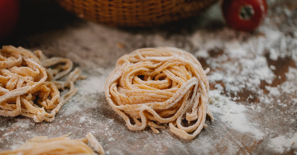 Underside of dough in proofing basket pulls apart - From above nests of fresh homemade uncooked spaghetti placed on wooden table with scattered flour in kitchen Underside of dough in proofing basket pulls apart - From above nests of fresh homemade uncooked spaghetti placed on wooden table with scattered flour in kitchen