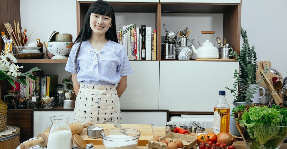 Use flour vs oil in rising dough - Happy young Asian woman standing near table with ingredients for dough Use flour vs oil in rising dough - Happy young Asian woman standing near table with ingredients for dough