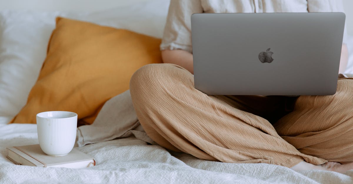 using crumbs mixture multiple times [is it safe?] - Crop faceless female in casual outfit sitting on bed with legs crossed holding laptop on knees with cup of coffee standing on notebook while working from home