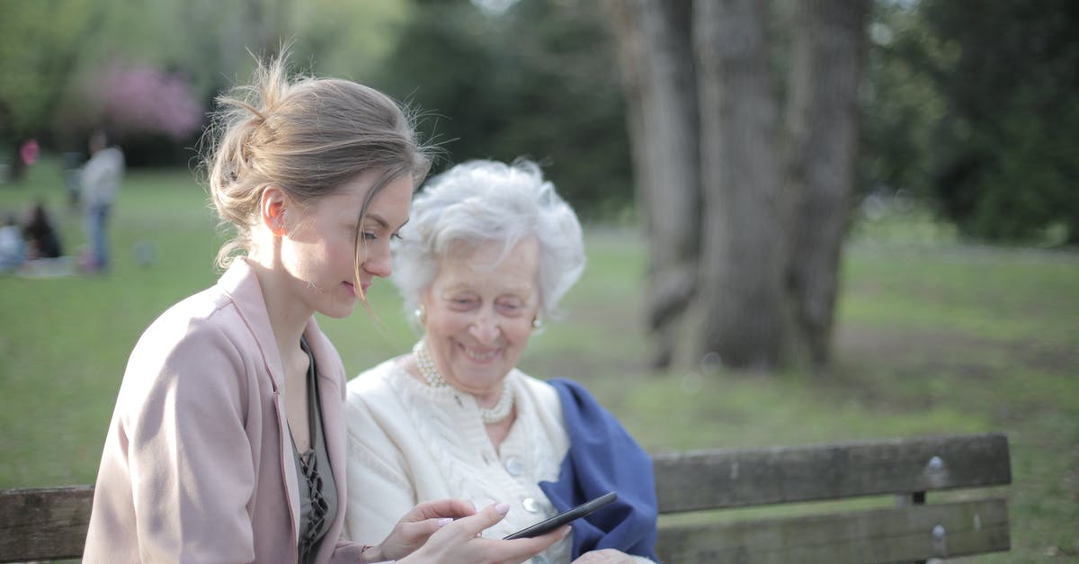 Using old vanilla beans - Side view of smiling adult female helping aged mom in using of mobile phone while sitting together in park Using old vanilla beans - Side view of smiling adult female helping aged mom in using of mobile phone while sitting together in park