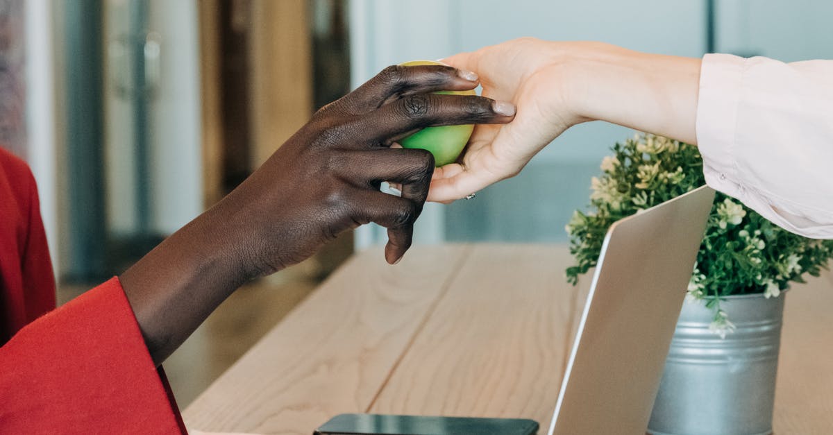 Using soft apples to make apple juice - Black businesswoman taking green apple from colleague at workplace Using soft apples to make apple juice - Black businesswoman taking green apple from colleague at workplace