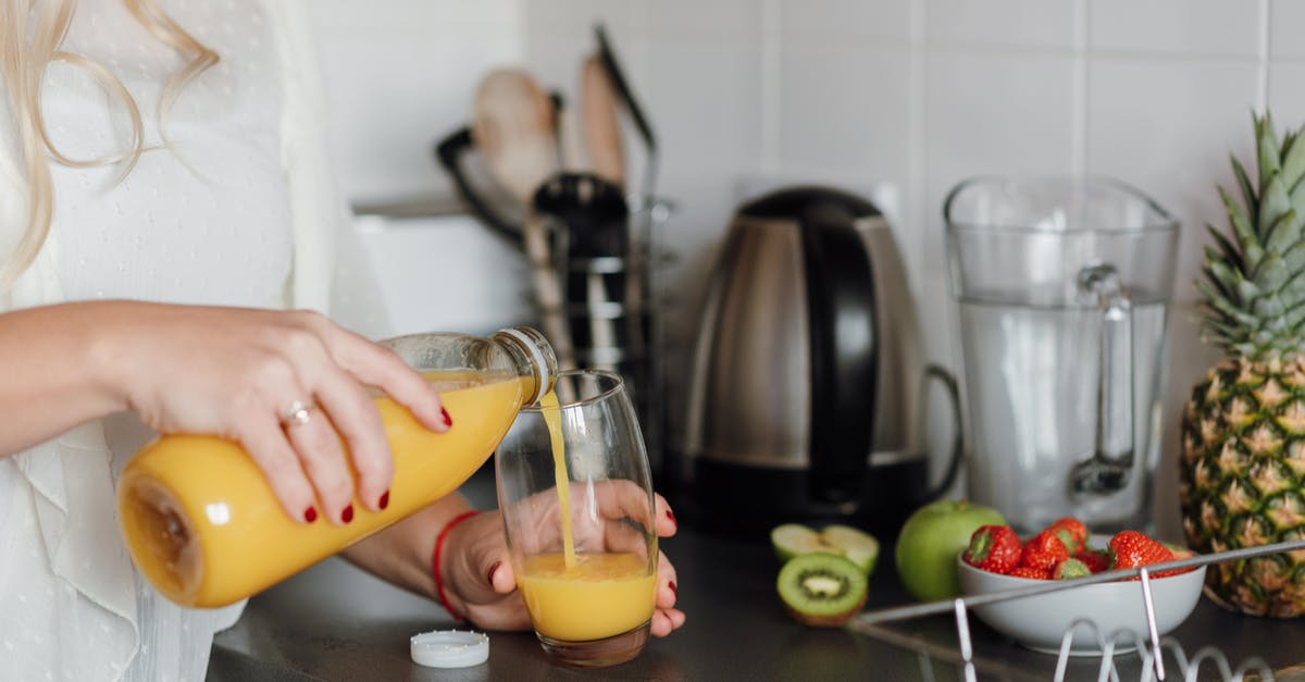 Using soft apples to make apple juice - Crop woman poring juice standing near table with fruits Using soft apples to make apple juice - Crop woman poring juice standing near table with fruits