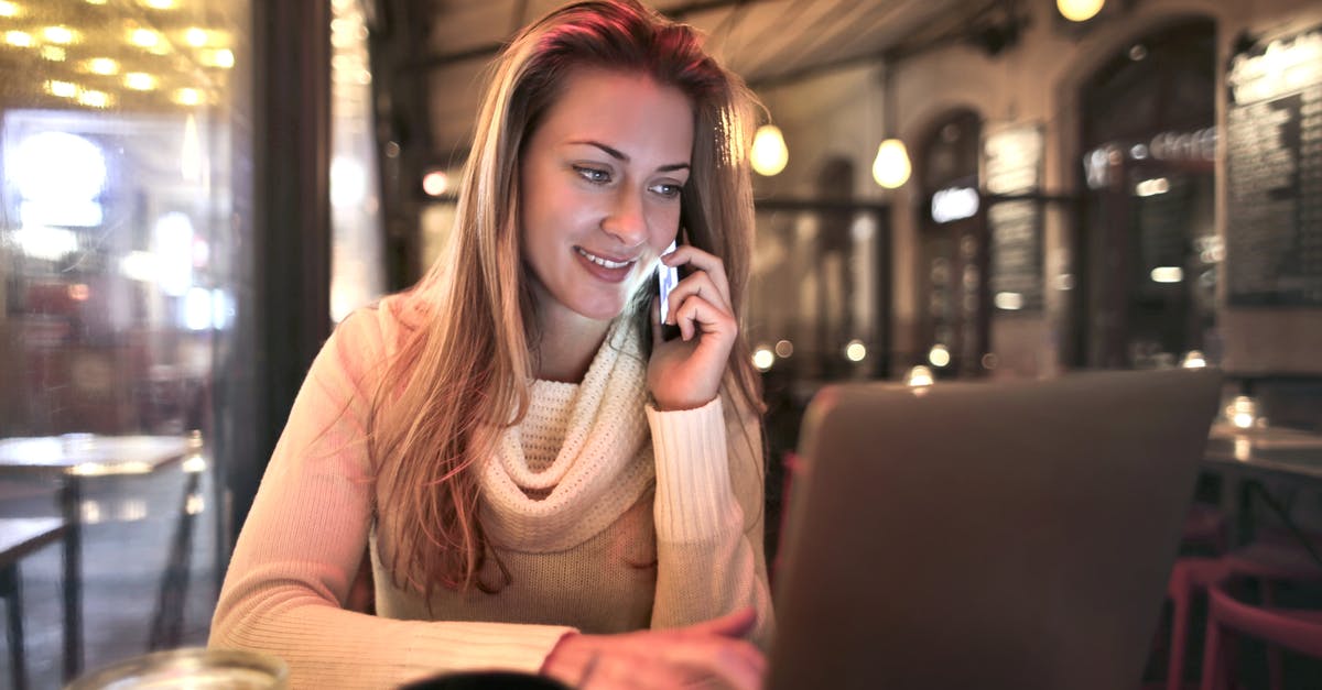 Warming refrigerated butter at a table in a restaurant - Content female wearing warm sweater sitting at table in cozy cafe and speaking on cellphone while resting in evening and browsing netbook Warming refrigerated butter at a table in a restaurant - Content female wearing warm sweater sitting at table in cozy cafe and speaking on cellphone while resting in evening and browsing netbook