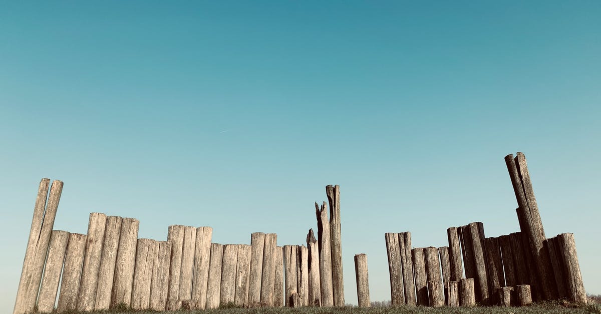 Was honey in ancient times different than now? - Natural wooden fence of rounded tree trunks with shabby surface and cracks on grass meadow under cloudless sky in daylight in countryside Was honey in ancient times different than now? - Natural wooden fence of rounded tree trunks with shabby surface and cracks on grass meadow under cloudless sky in daylight in countryside