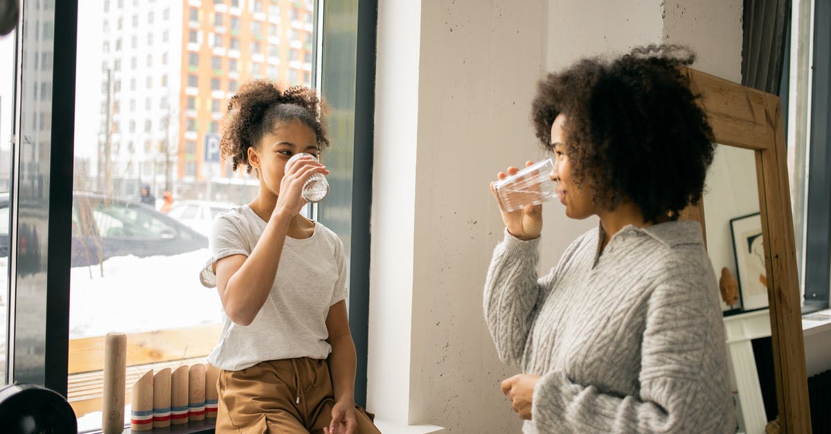 Water content of salted butter - Positive African American mother with daughter in casual wear looking at each other while drinking water from glasses in light room Water content of salted butter - Positive African American mother with daughter in casual wear looking at each other while drinking water from glasses in light room