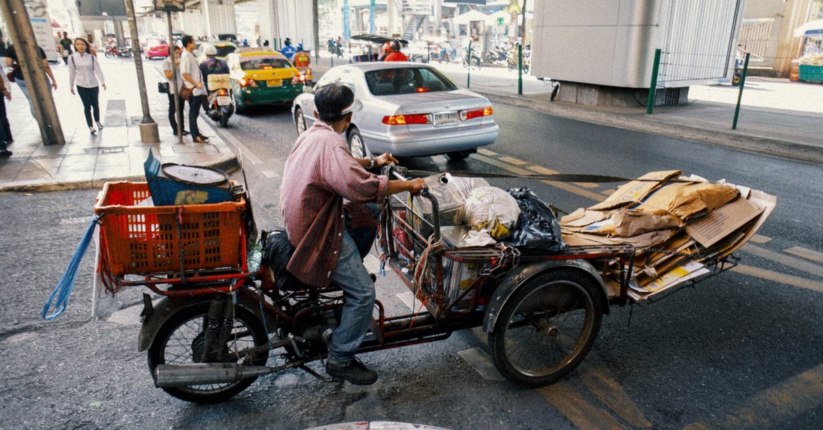 What's the proper way to package dough? - Full body side view of ethnic man carrying packages and cartons on tricycle while crossing asphalt road What's the proper way to package dough? - Full body side view of ethnic man carrying packages and cartons on tricycle while crossing asphalt road