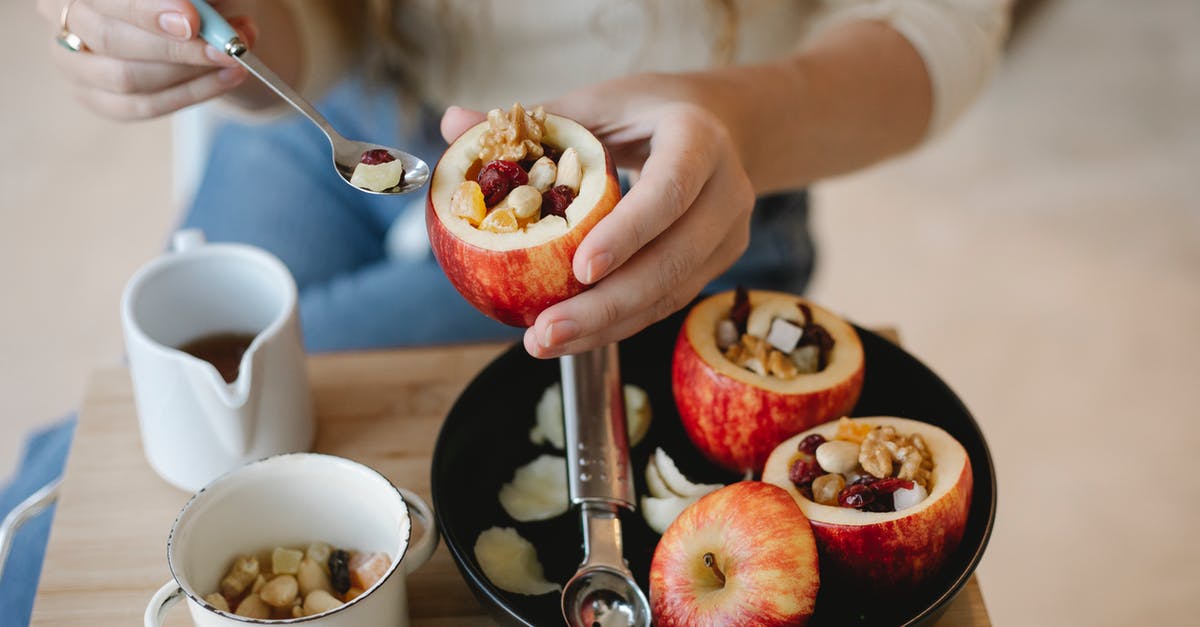 What's the purpose of syrup in toffee apples? - Faceless female cook with syrup in spoon and filled red apple during cooking process at home What's the purpose of syrup in toffee apples? - Faceless female cook with syrup in spoon and filled red apple during cooking process at home