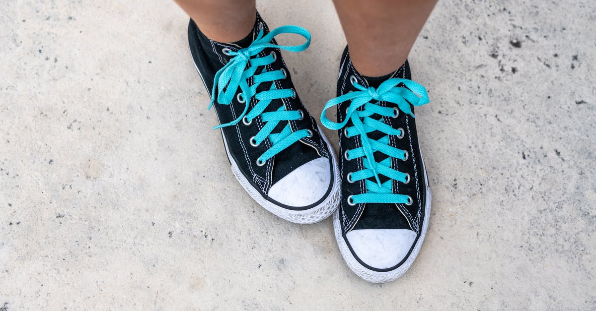What are certified synthetic colors? - Top view of crop anonymous person in trendy footwear with blue shoelaces on gray background in daytime What are certified synthetic colors? - Top view of crop anonymous person in trendy footwear with blue shoelaces on gray background in daytime