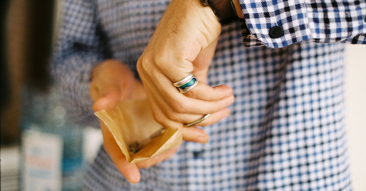 What are possible alternatives for parchment paper when baking cream puffs? [duplicate] - Crop unrecognizable male in checkered shirt holding parchment paper with cannabis and milling hemp with scissors while standing in daylight