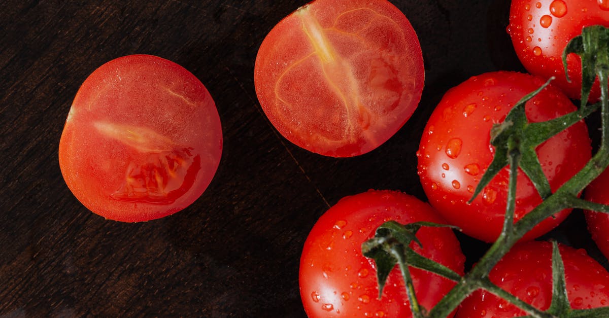 What are some recommended methods of cleaning wooden cutting boards? - From above closeup of cut on halves fresh tomato and branch of ripe tomatoes with drops placed on wet wooden cutting board What are some recommended methods of cleaning wooden cutting boards? - From above closeup of cut on halves fresh tomato and branch of ripe tomatoes with drops placed on wet wooden cutting board