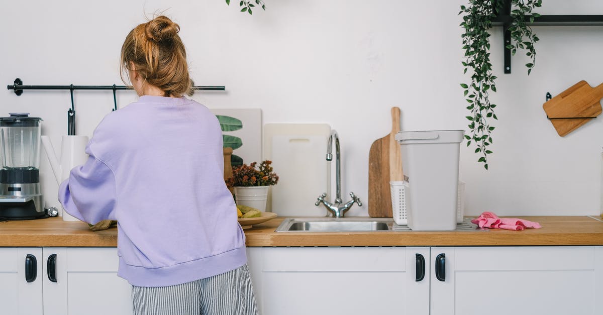 What are some recommended methods of cleaning wooden cutting boards? - Woman standing at wooden counter in kitchen in daytime What are some recommended methods of cleaning wooden cutting boards? - Woman standing at wooden counter in kitchen in daytime