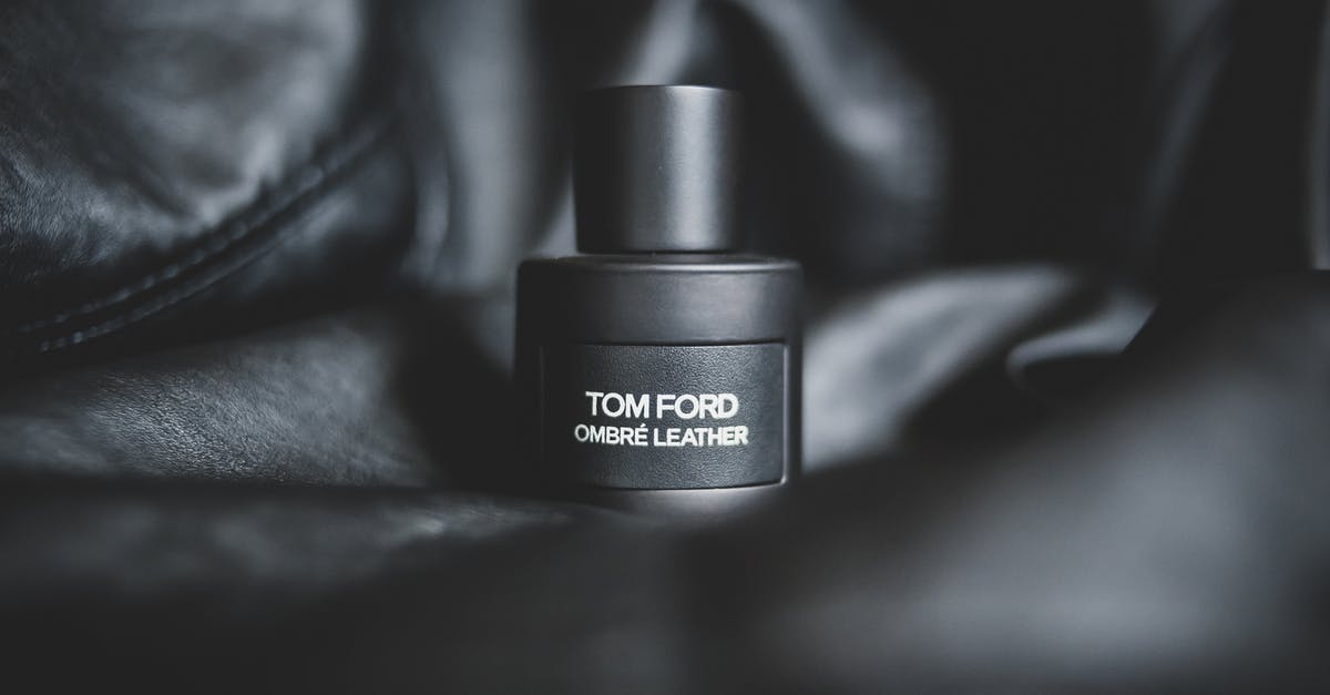 What are the black spots on the lid of my expensive oil bottle? - Closeup of black plastic bottle with expensive fragrance placed on black leather material
