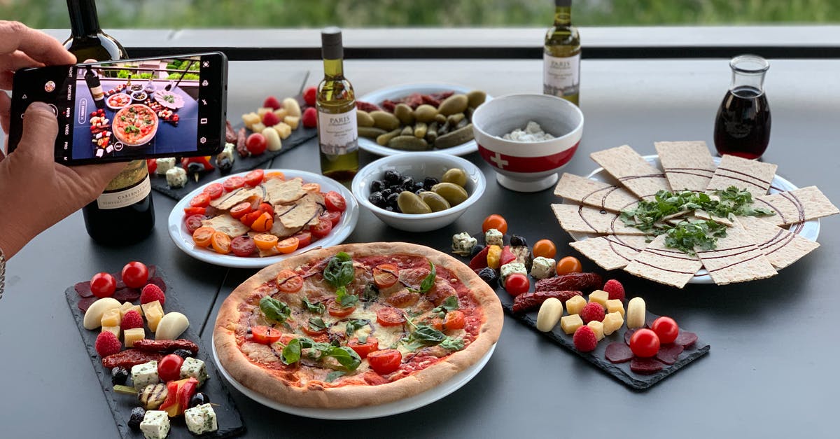 What are the four cheeses generally used in"four-cheese" pizzas? - Unrecognizable person photographing table with pizza and assorted snacks What are the four cheeses generally used in"four-cheese" pizzas? - Unrecognizable person photographing table with pizza and assorted snacks