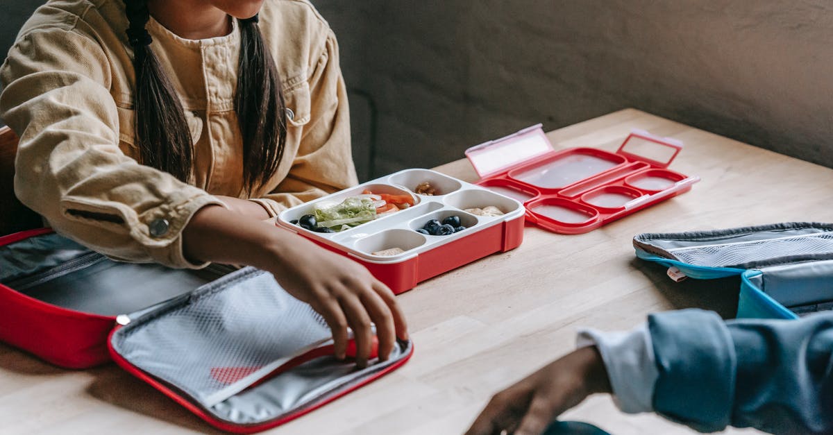 What compound can make crunchy biscuits? - From above of crop anonymous ethnic schoolkids with lunch boxes full of delicious food in classroom What compound can make crunchy biscuits? - From above of crop anonymous ethnic schoolkids with lunch boxes full of delicious food in classroom