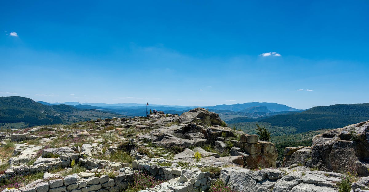 What could be the history of this pan? - Mountains and Ancient Ruins with Tourists in Distance What could be the history of this pan? - Mountains and Ancient Ruins with Tourists in Distance