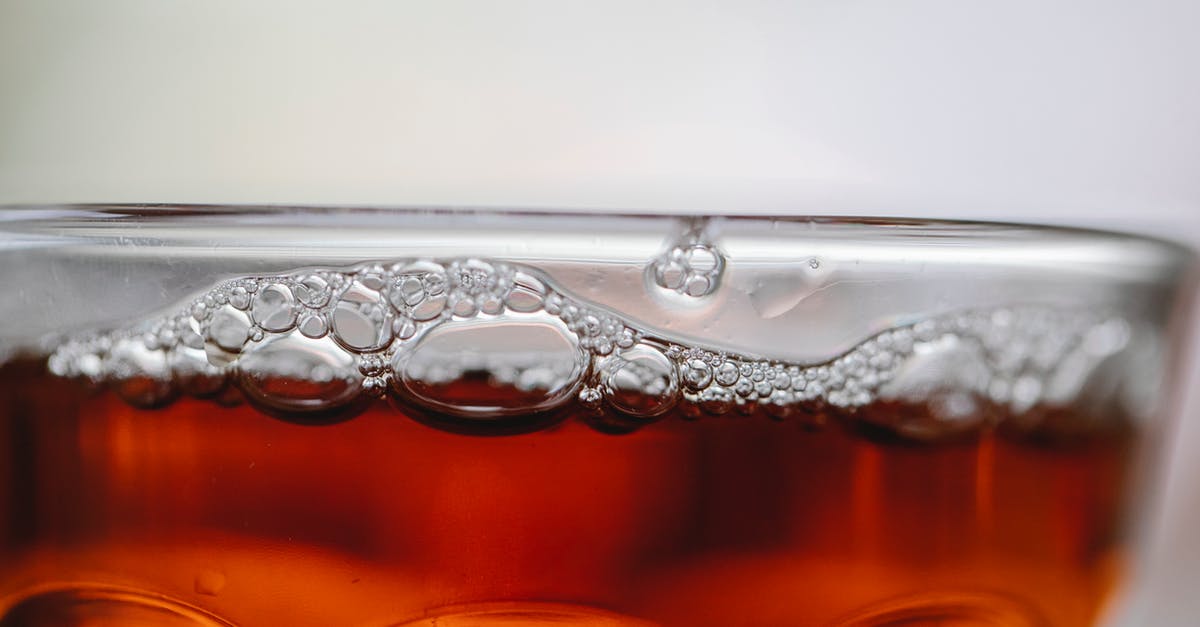 What determines if a juice is clear or opaque? - Closeup of alcoholic drink with small bubbles in clean transparent glass on white background What determines if a juice is clear or opaque? - Closeup of alcoholic drink with small bubbles in clean transparent glass on white background