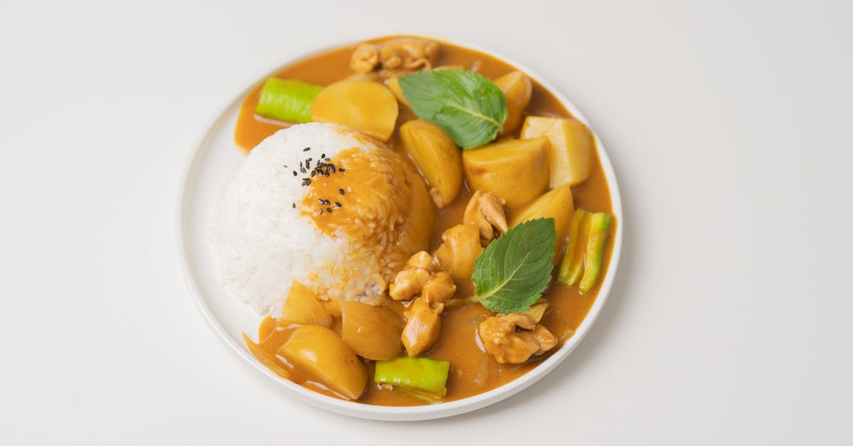 What determines spice level in Indian cuisine? - From above of appetizing dish of Indian cuisine curry made of vegetables and meat and served with rice and green leaves
