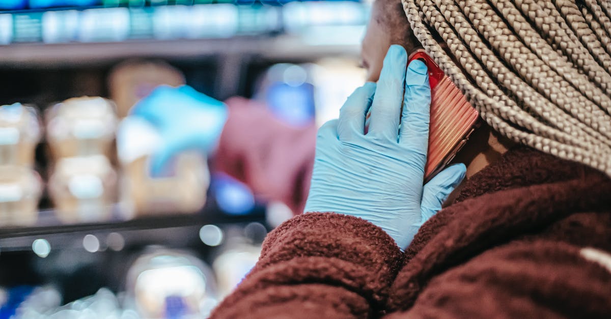 What do you call it and where to buy some - Side view of crop African American female customer in latex gloves with braids having phone call while picking food from shelf in grocery store What do you call it and where to buy some - Side view of crop African American female customer in latex gloves with braids having phone call while picking food from shelf in grocery store