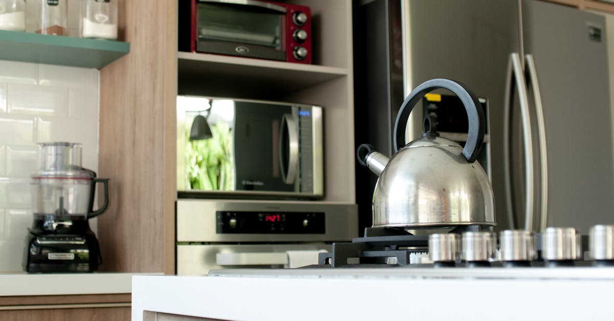 What does a fridge do apart from storing and cooling? - Metal kettle on stove in modern kitchen What does a fridge do apart from storing and cooling? - Metal kettle on stove in modern kitchen