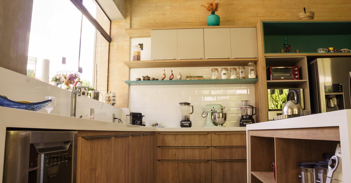 What does a fridge do apart from storing and cooling? - From below wooden cabinets and shelves of cozy kitchen with stainless steel appliances in sunlight What does a fridge do apart from storing and cooling? - From below wooden cabinets and shelves of cozy kitchen with stainless steel appliances in sunlight