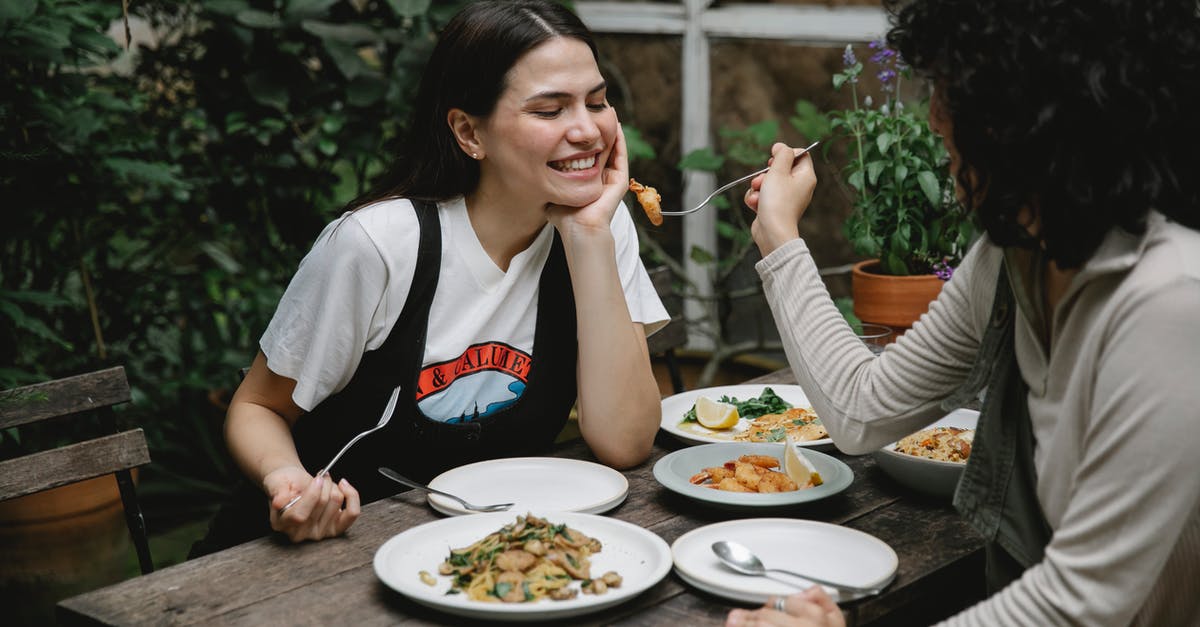What does adding dark rum give to a fajita stir-fry? - Female giving food on fork to cheerful friend while having lunch in outdoor terrace What does adding dark rum give to a fajita stir-fry? - Female giving food on fork to cheerful friend while having lunch in outdoor terrace