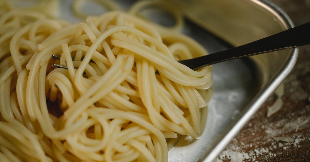 What does al dente really mean? - Cooked spaghetti and fork placed in steel bowl What does al dente really mean? - Cooked spaghetti and fork placed in steel bowl