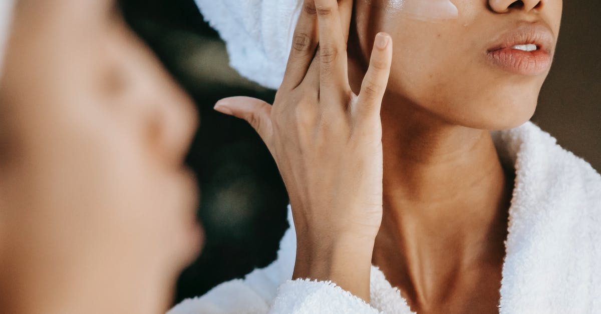 What does make ice cream smooth and silky? - Crop unrecognizable young ethnic female in terry robe applying moisturizing cream on cheek while reflecting in mirror What does make ice cream smooth and silky? - Crop unrecognizable young ethnic female in terry robe applying moisturizing cream on cheek while reflecting in mirror