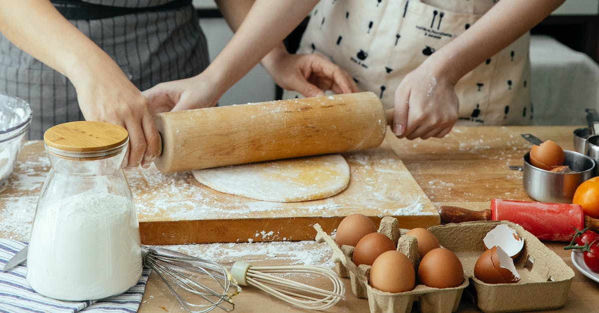 What does yeast do to flour? - Unrecognizable women rolling dough together on board on table with jar with flour carton with eggs and whisks What does yeast do to flour? - Unrecognizable women rolling dough together on board on table with jar with flour carton with eggs and whisks