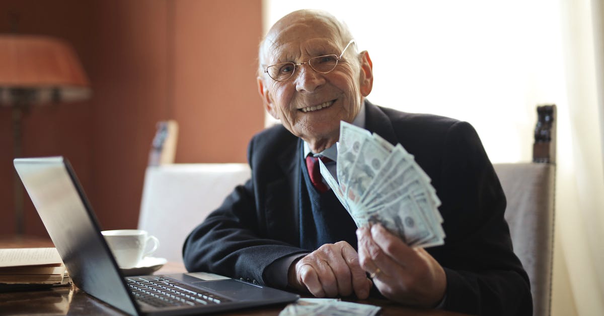 What factors lead to rich crema on espresso? - Happy senior businessman holding money in hand while working on laptop at table What factors lead to rich crema on espresso? - Happy senior businessman holding money in hand while working on laptop at table