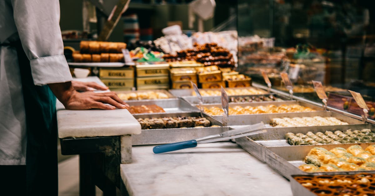 What factors should I consider when buying kitchen tongs? - Crop anonymous male seller at counter with assorted traditional Turkish sweets in market What factors should I consider when buying kitchen tongs? - Crop anonymous male seller at counter with assorted traditional Turkish sweets in market