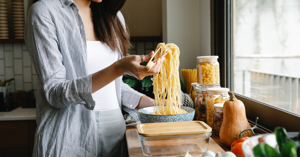 What factors should I consider when buying kitchen tongs? - Side view of cheerful female with long cooked spaghetti on tongs standing in kitchen while preparing delicious pasta at home What factors should I consider when buying kitchen tongs? - Side view of cheerful female with long cooked spaghetti on tongs standing in kitchen while preparing delicious pasta at home