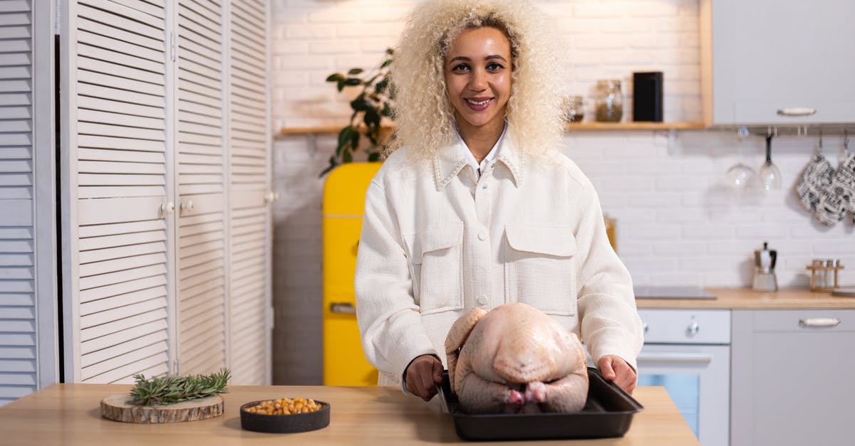 What is a good way to cook Turkey Chops? - Smiling female looking at camera while standing at counter with uncooked turkey on tray during dinner preparation in modern kitchen What is a good way to cook Turkey Chops? - Smiling female looking at camera while standing at counter with uncooked turkey on tray during dinner preparation in modern kitchen
