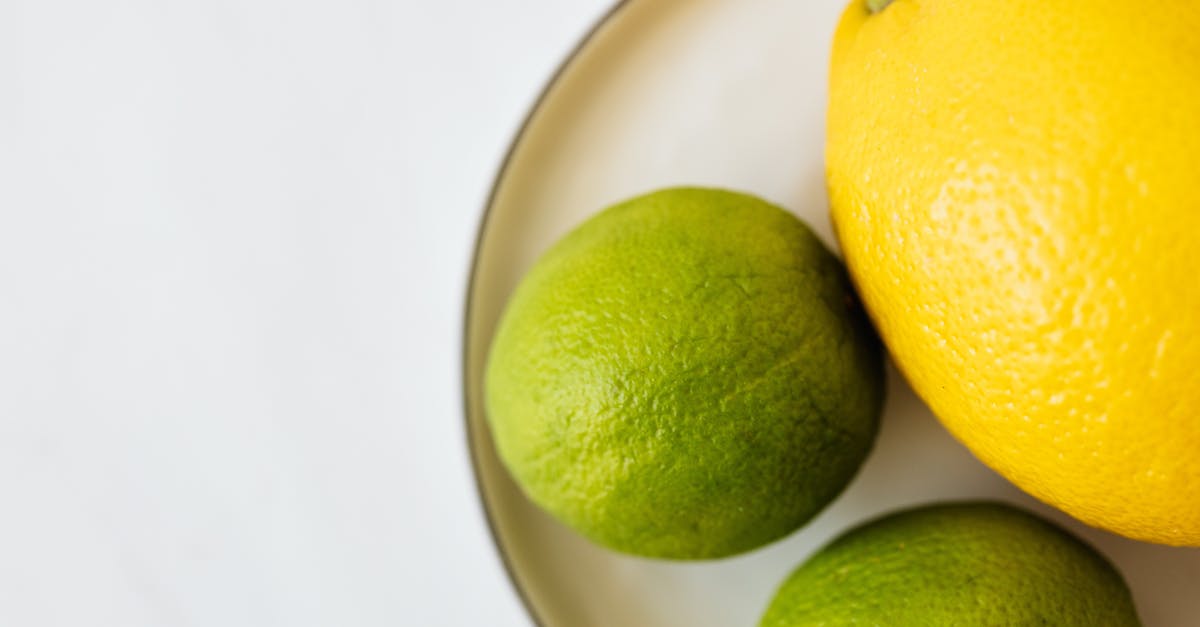 What is an elegant way to serve whole duck livers? [closed] - Top view of closeup whole ripe lemon and limes served on white metal plate on white surface