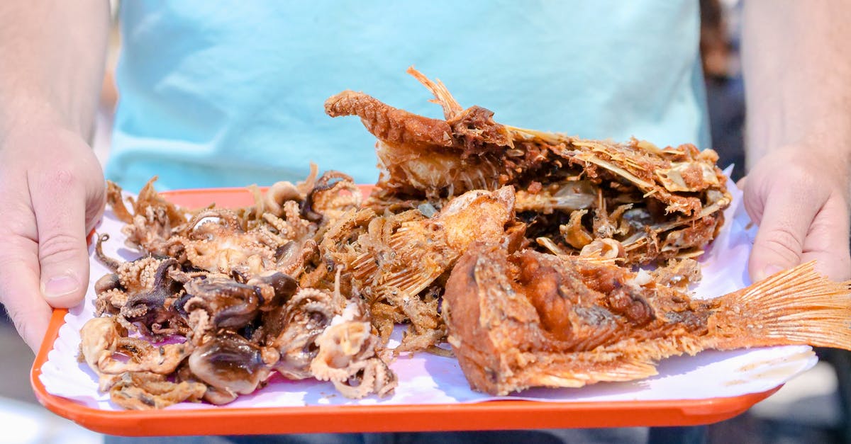What is helping fried fish have more flavour? - Man in Blue T-Shirt Holding Plate with Fried Seafood