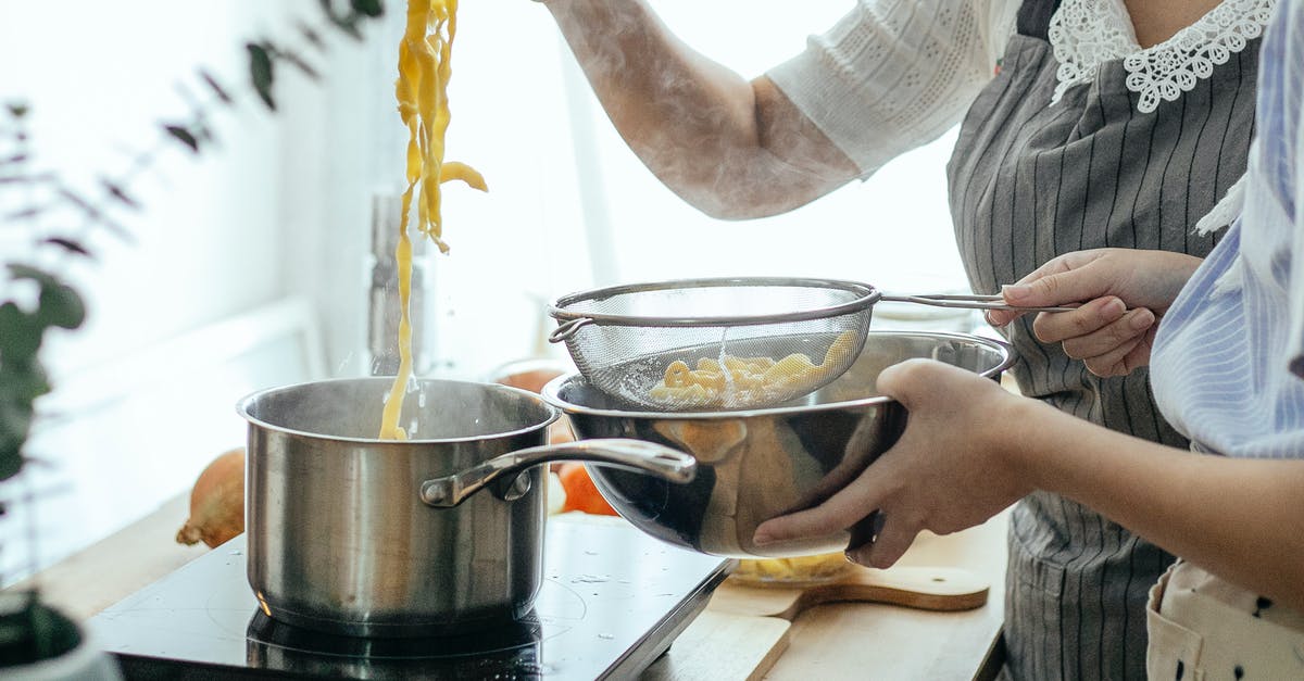 What is the benefit of a pasta pot with an inset? - Unrecognizable female cooks putting pasta from pot into sieve while cooking lunch at table with stove in kitchen on blurred background What is the benefit of a pasta pot with an inset? - Unrecognizable female cooks putting pasta from pot into sieve while cooking lunch at table with stove in kitchen on blurred background