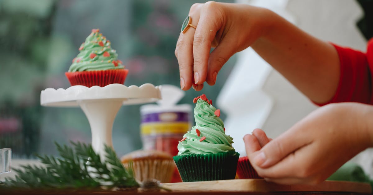 What is the best technique to put icing on plastic? - Unrecognizable female sprinkling topping on green frosting of cupcake while standing near windowsill with wooden board and coniferous branch on blurred background What is the best technique to put icing on plastic? - Unrecognizable female sprinkling topping on green frosting of cupcake while standing near windowsill with wooden board and coniferous branch on blurred background