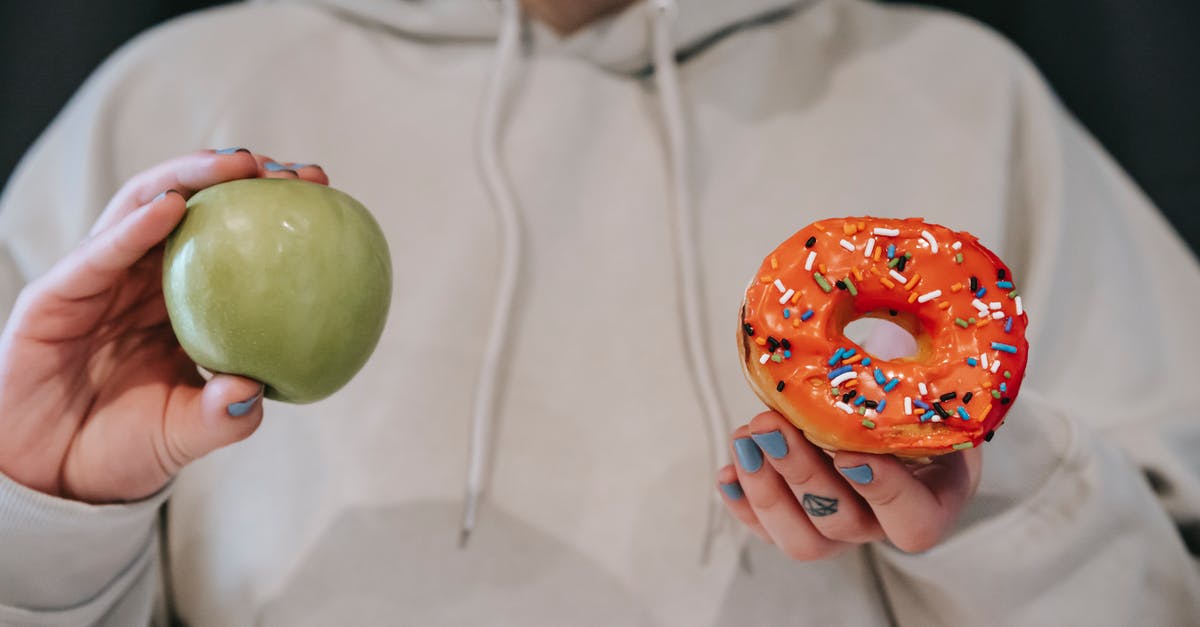 What is the difference between doughnut and krapfen? - Crop faceless woman demonstrating ripe green apple and sweet doughnut What is the difference between doughnut and krapfen? - Crop faceless woman demonstrating ripe green apple and sweet doughnut