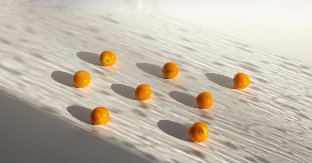 What is the difference between grape and cherry tomatoes? - Sweet yellow ripe cherry tomatoes arranged on white surface in shadows in light studio What is the difference between grape and cherry tomatoes? - Sweet yellow ripe cherry tomatoes arranged on white surface in shadows in light studio