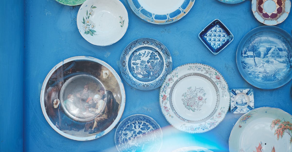 What is the difference between these tableware flatware and cutlery? - Assorted vintage plates of different sizes and ornaments hanging on bright blue wall in light studio What is the difference between these tableware flatware and cutlery? - Assorted vintage plates of different sizes and ornaments hanging on bright blue wall in light studio