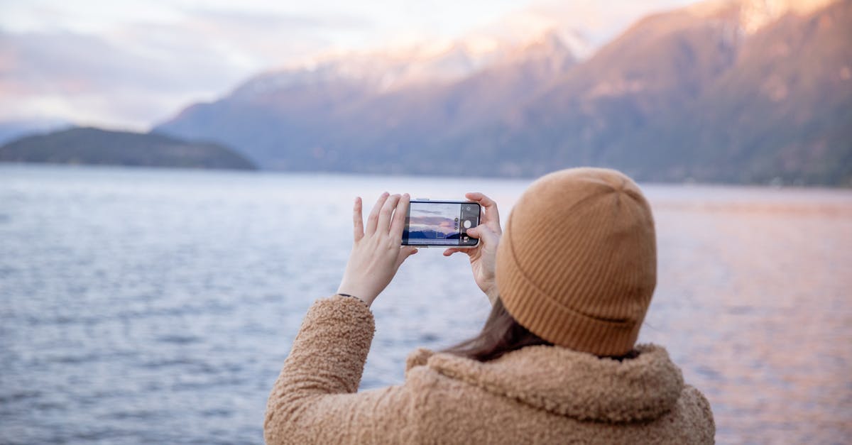 What is the difference between using hot water and cold water when making regular pastry? - Back view of unrecognizable female tourist in warm coat and hat taking photo on smartphone while standing on coast near water and enjoying seascape during trip