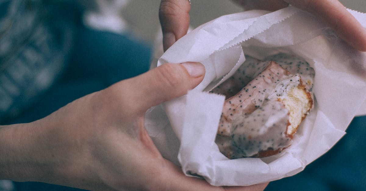 What is the easiest way to grind poppy seeds? - From above of crop unrecognizable person showing tasty sweet donut with glaze in organic bag on street What is the easiest way to grind poppy seeds? - From above of crop unrecognizable person showing tasty sweet donut with glaze in organic bag on street