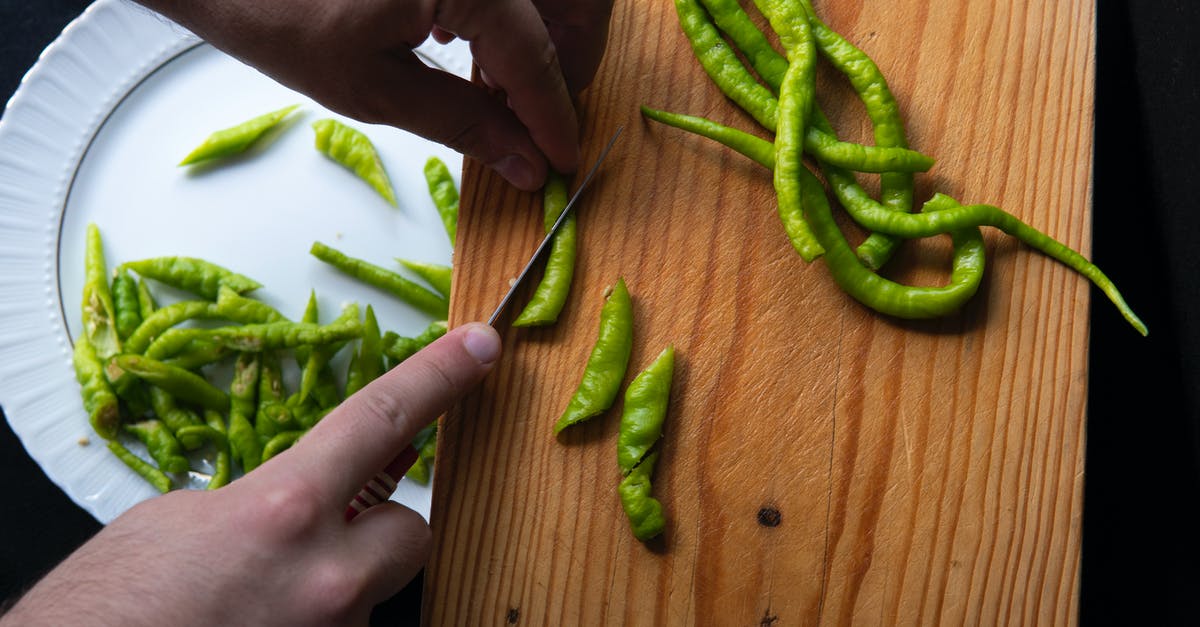 What is the hottest part of a chili/chilli/chile pepper? - From above hands of crop unrecognizable person cutting hot peppers on cutting board and putting slices on plate What is the hottest part of a chili/chilli/chile pepper? - From above hands of crop unrecognizable person cutting hot peppers on cutting board and putting slices on plate
