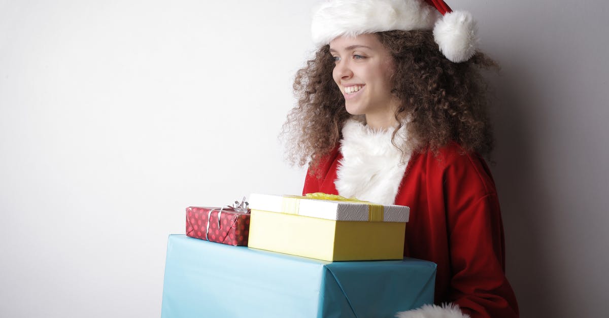 What is the magic in packaged pudding mixes? - Side view of cheerful female with curly hair wearing Santa hat and costume standing with stack of wrapped presents on white background in studio and looking away What is the magic in packaged pudding mixes? - Side view of cheerful female with curly hair wearing Santa hat and costume standing with stack of wrapped presents on white background in studio and looking away