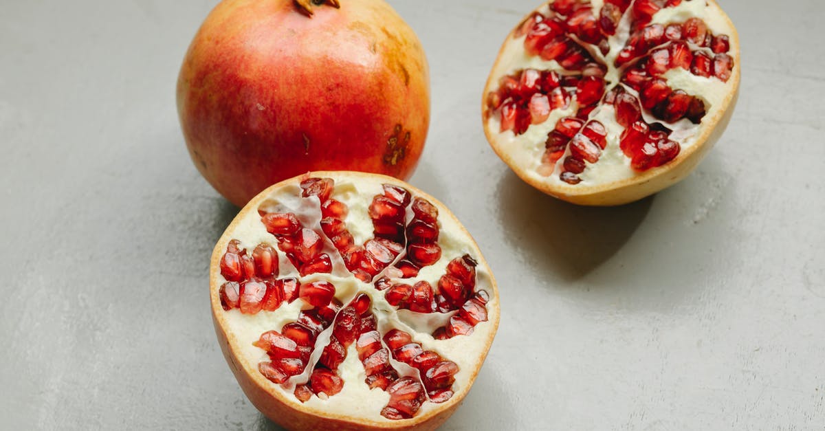 What is the meaning of the term whole grain? - Ripe whole and halved pomegranates with red seeds placed on gray background in studio